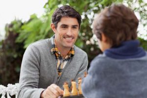 man smiling playing chess after sleep apnea treatment helped with his mental health symptoms from sleep apnea
